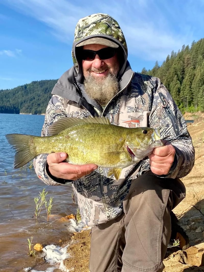 Man on a boat holding a Smallmouth Bass by a digital scale.