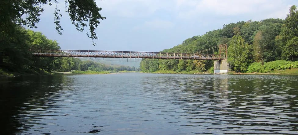 Kellams Bridge spanning the Delaware River with forested banks.