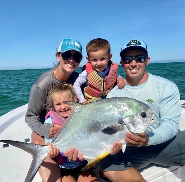 Family on a boat holding a large Permit.