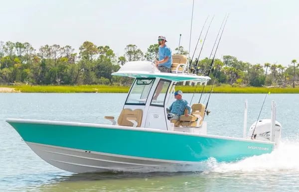 Smiling man in sunglasses holding a Spanish Mackerel on a boat