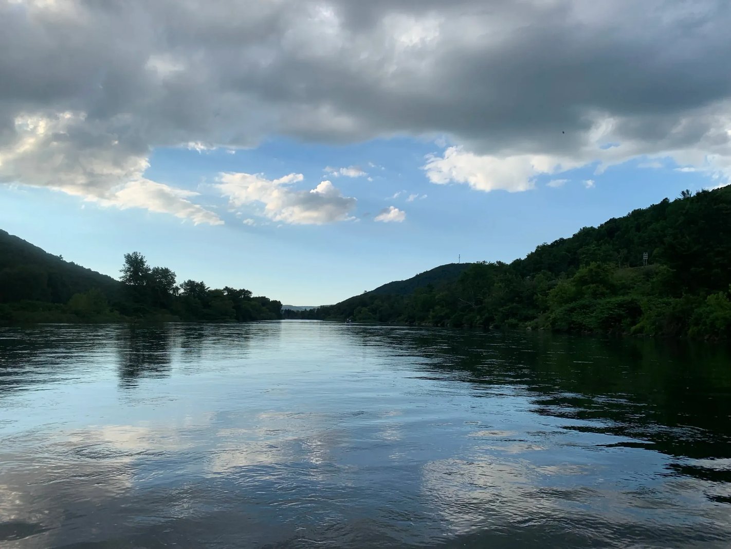 Wide river with forested banks under a cloudy sky