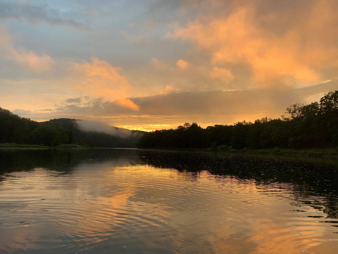 River at sunset with orange and pink clouds reflecting on the water