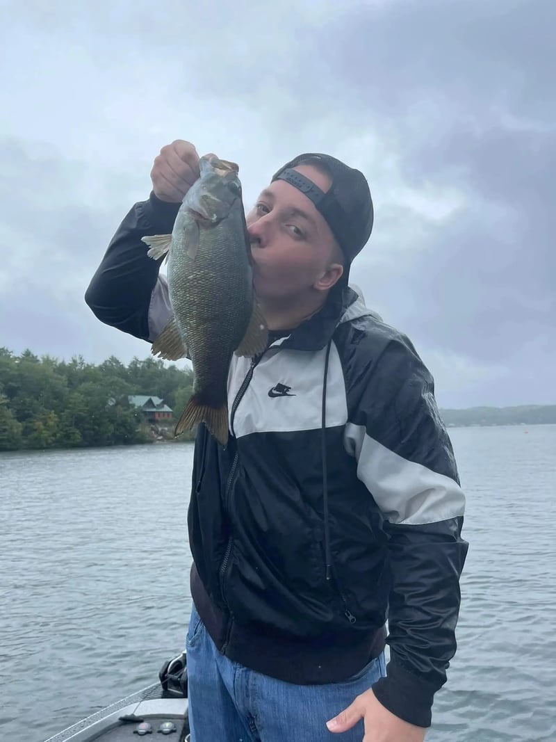 Man in sunglasses and a cap holding a large freshwater drum on a boat