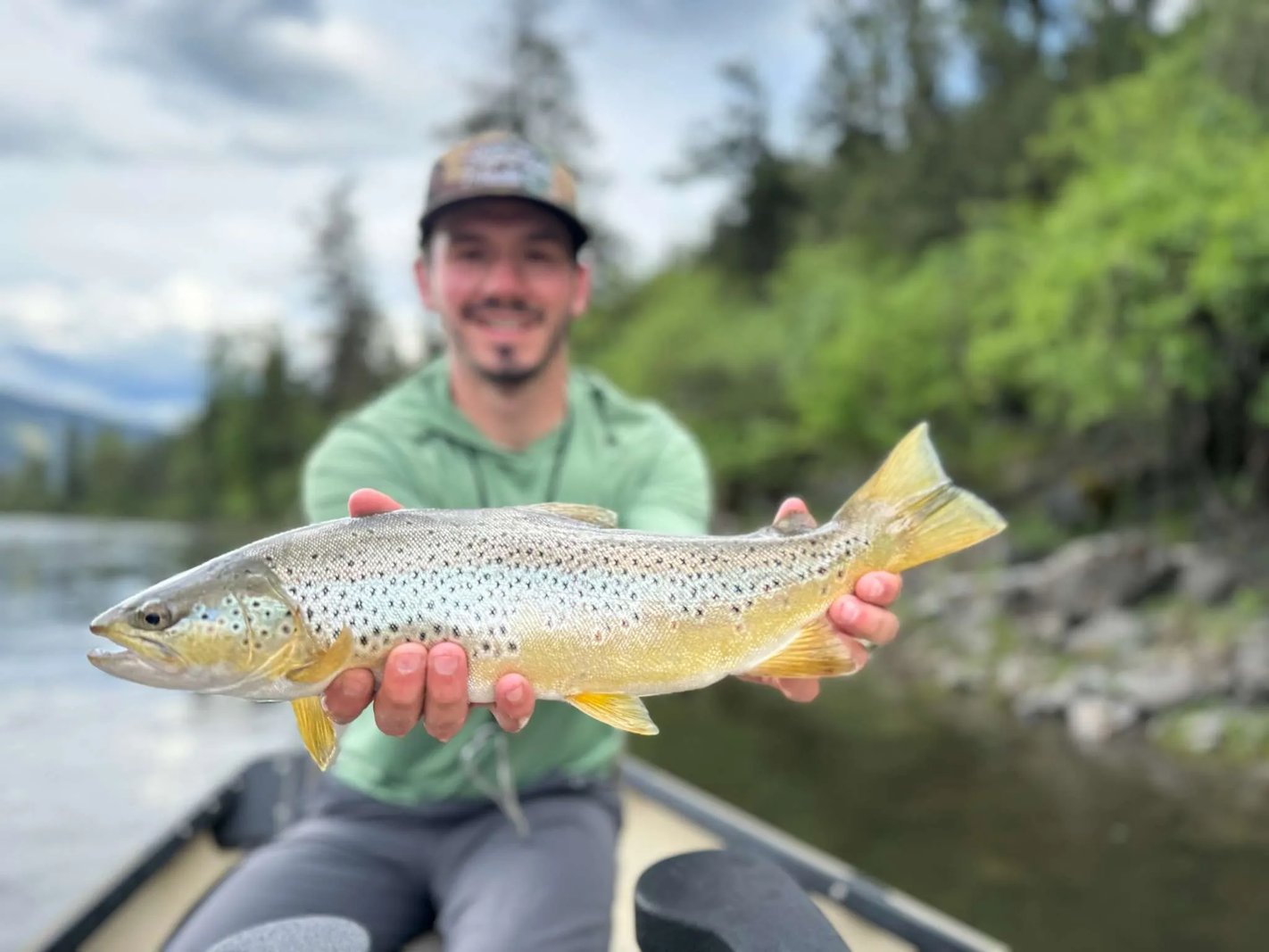 Angler in waders holding two Rainbow Trout submerged in a rocky river