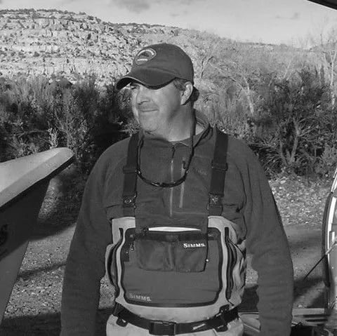 Man in waders and a cap, black and white portrait.
