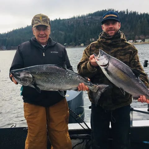 Angler on a boat holding a very large, red-colored King Salmon.