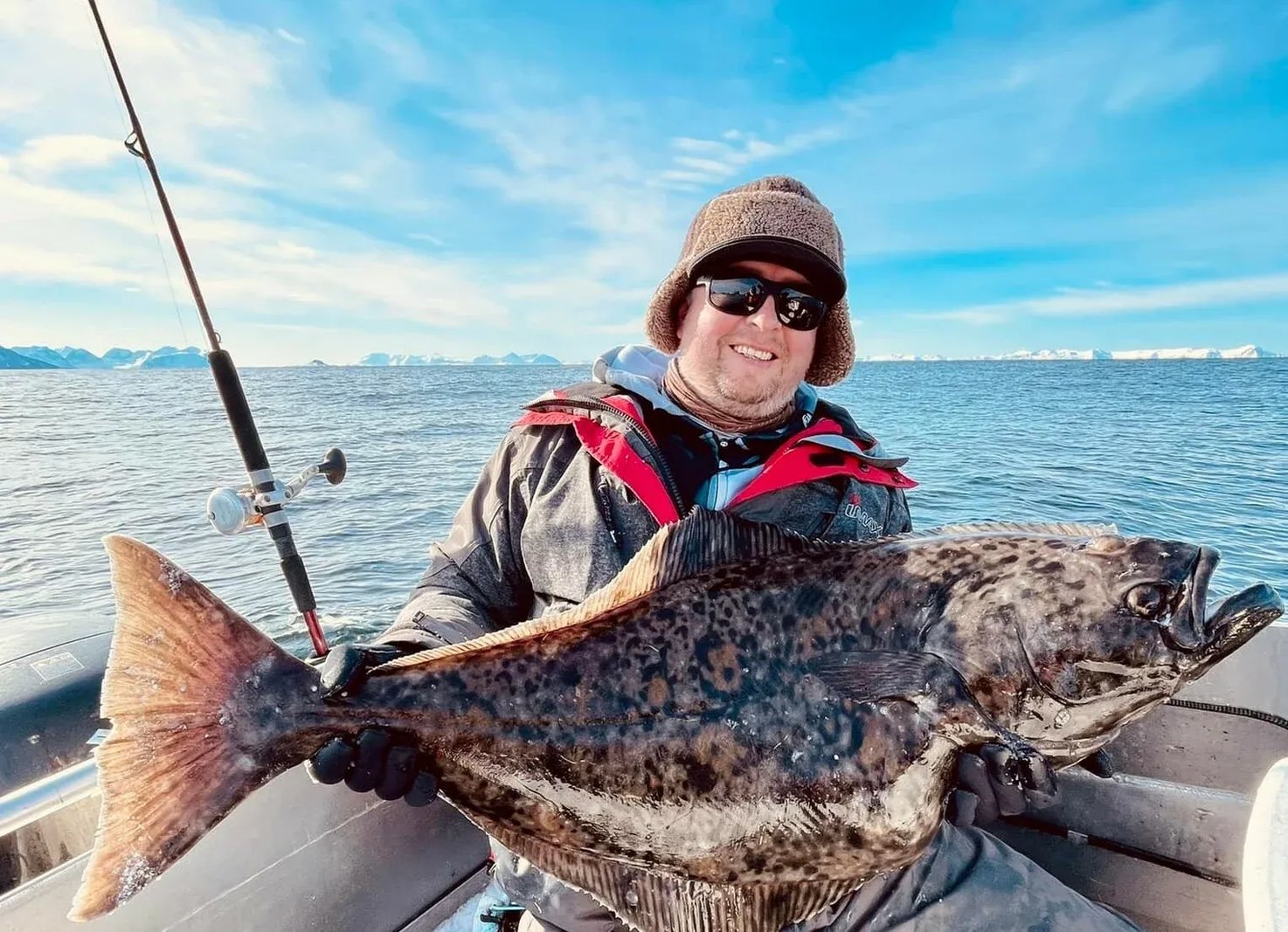 Three anglers on a boat proudly displaying a large Halibut