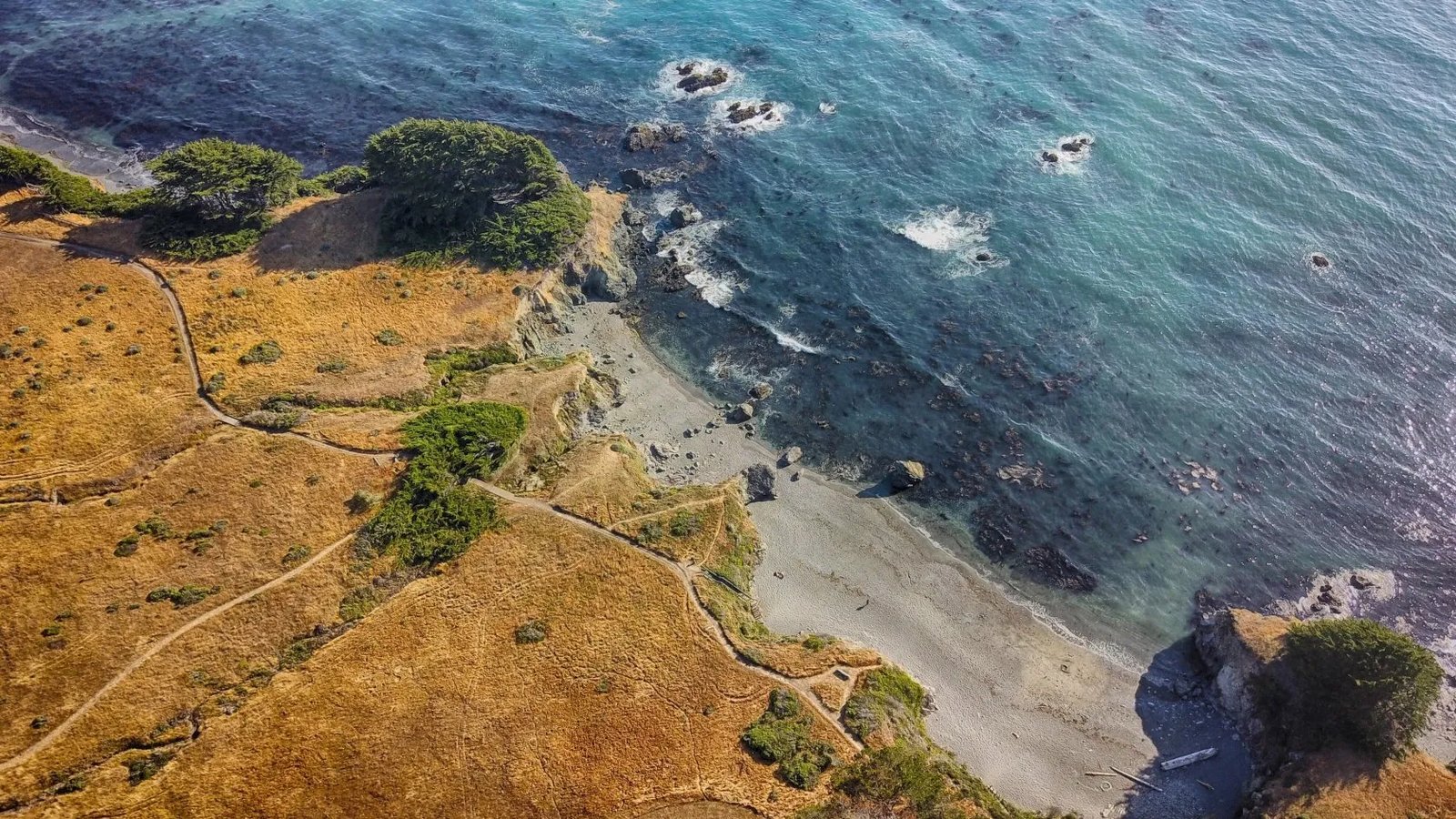 Aerial view of a rugged coastline with a sandy beach and blue ocean