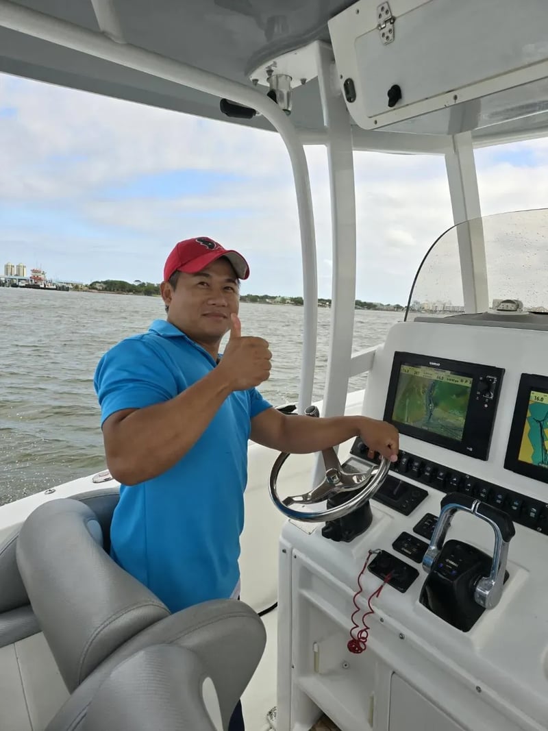 Captain at the helm of a boat, giving a thumbs up.