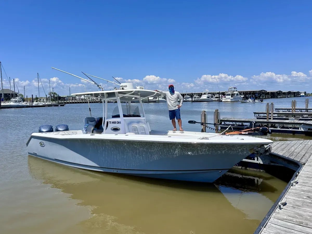 White center console boat docked in calm water under a blue sky.