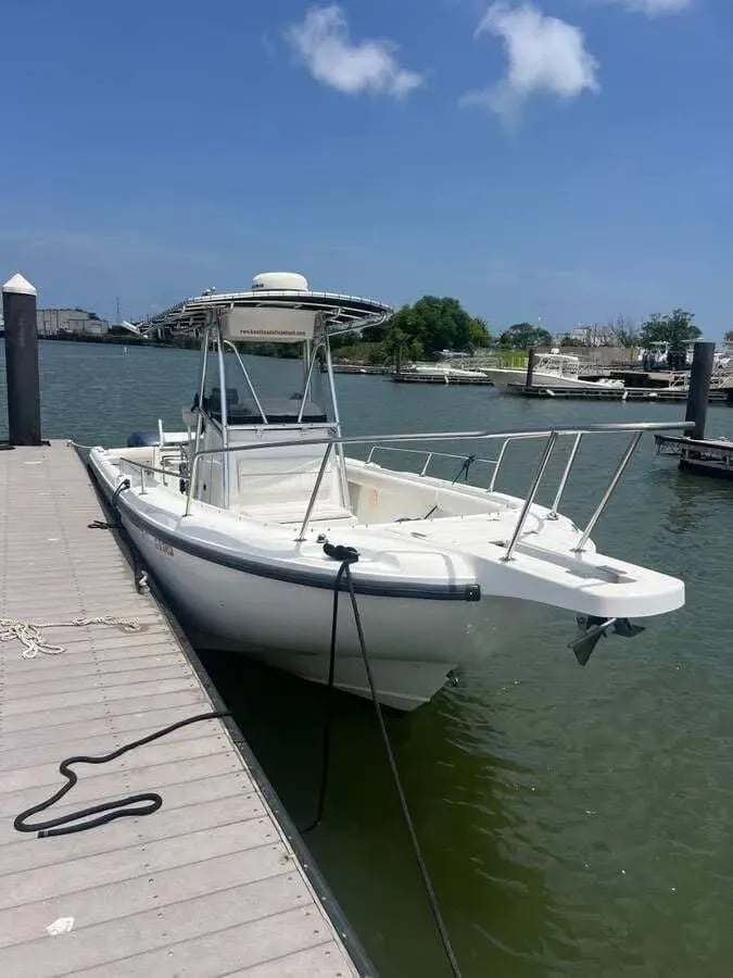 White Boston Whaler center console boat tied to a wooden dock.