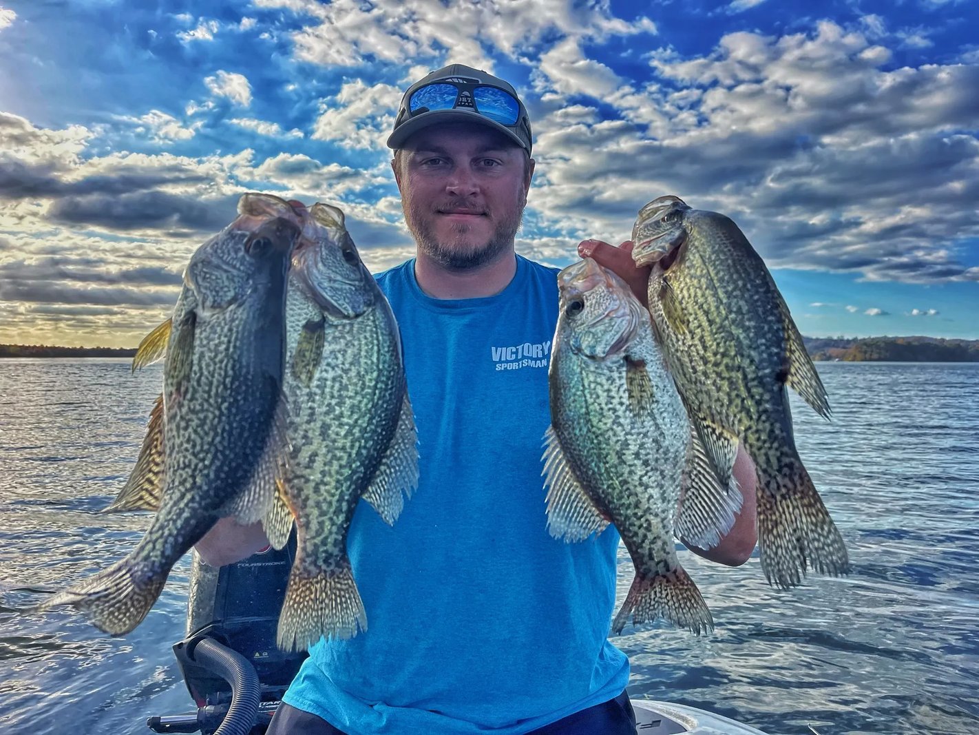 Angler holding a stringer of Crappie against a dramatic cloudy sky
