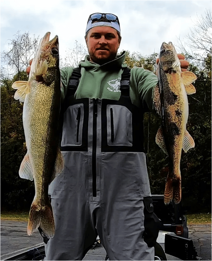 Two anglers fishing from a blue bass boat on a wide lake with green hills