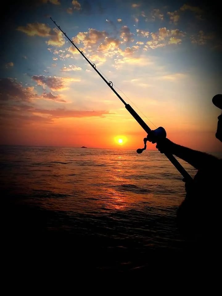 Two anglers on a boat deck holding a large Bluefin Tuna