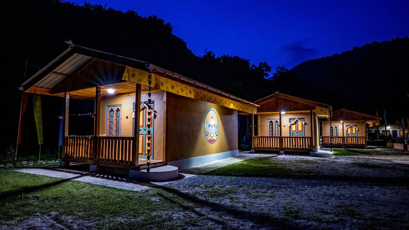 Wooden lodge buildings lit up at night against a dark mountain backdrop.