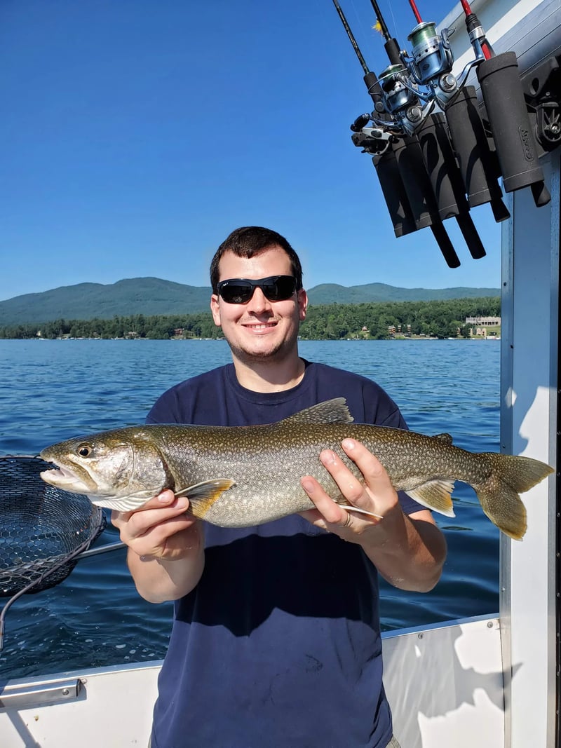 Two anglers holding smallmouth bass on a boat under a clear sky