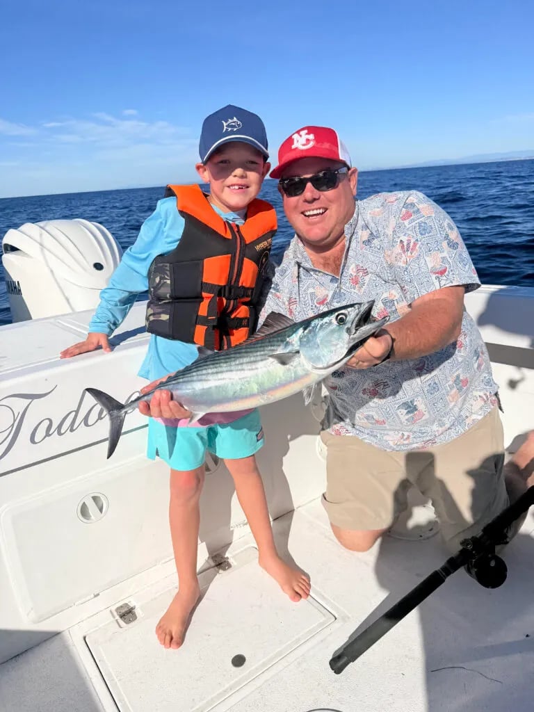 Angler and child holding a Bonito on a boat.