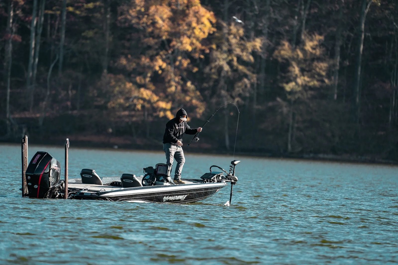 Woman in white shirt holding a Largemouth Bass on a boat under a blue sky