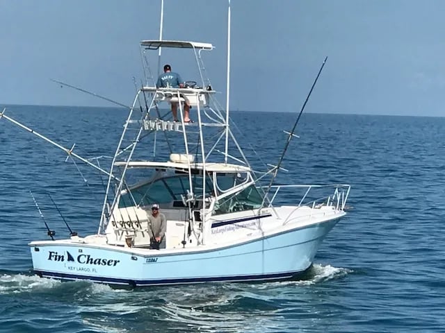 Light blue sportfishing boat 'Fin Chaser' running on blue water.