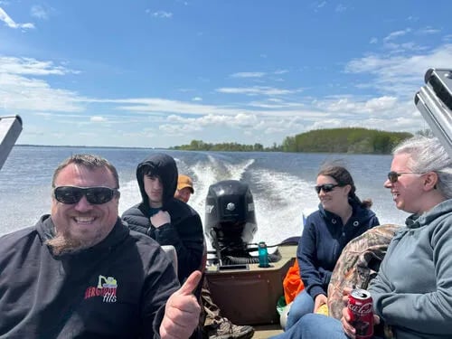 Group of people on a boat underway on a sunny day with a wake behind them