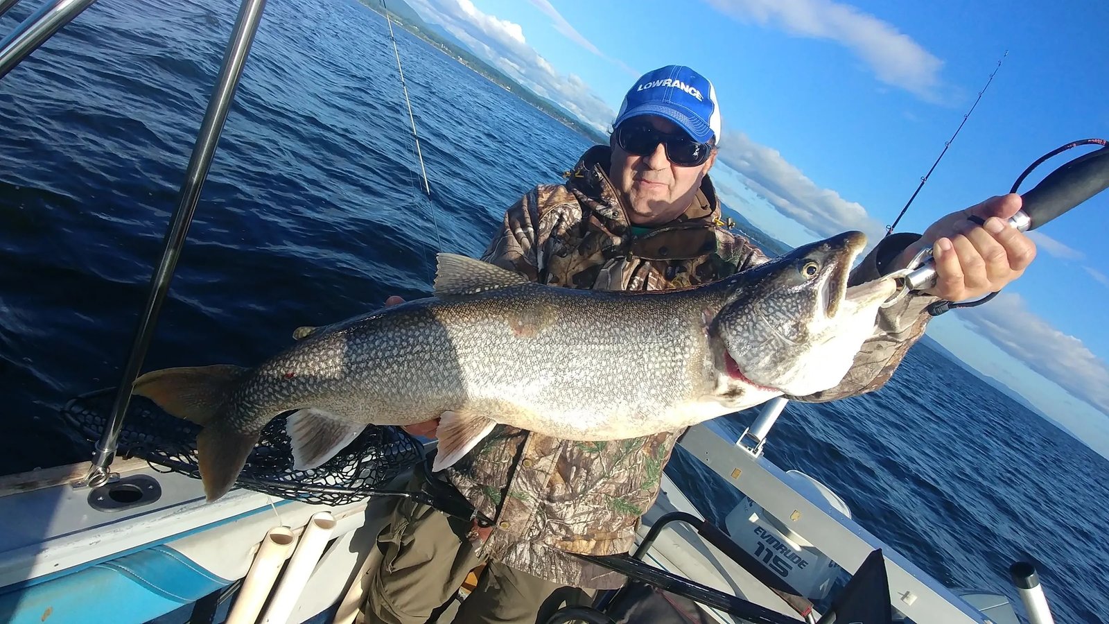 Family of four on a boat proudly holding a large Striped Bass.