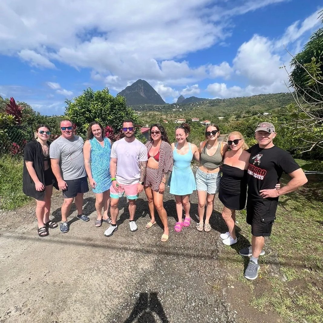 Group of tourists smiling with the iconic Pitons mountains in the background