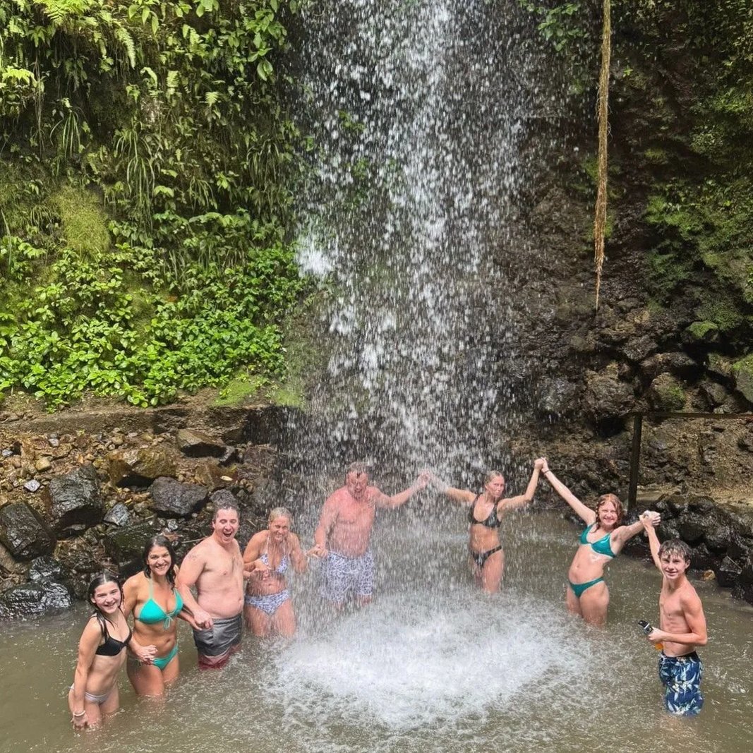 Large group of people holding hands under a cascading waterfall