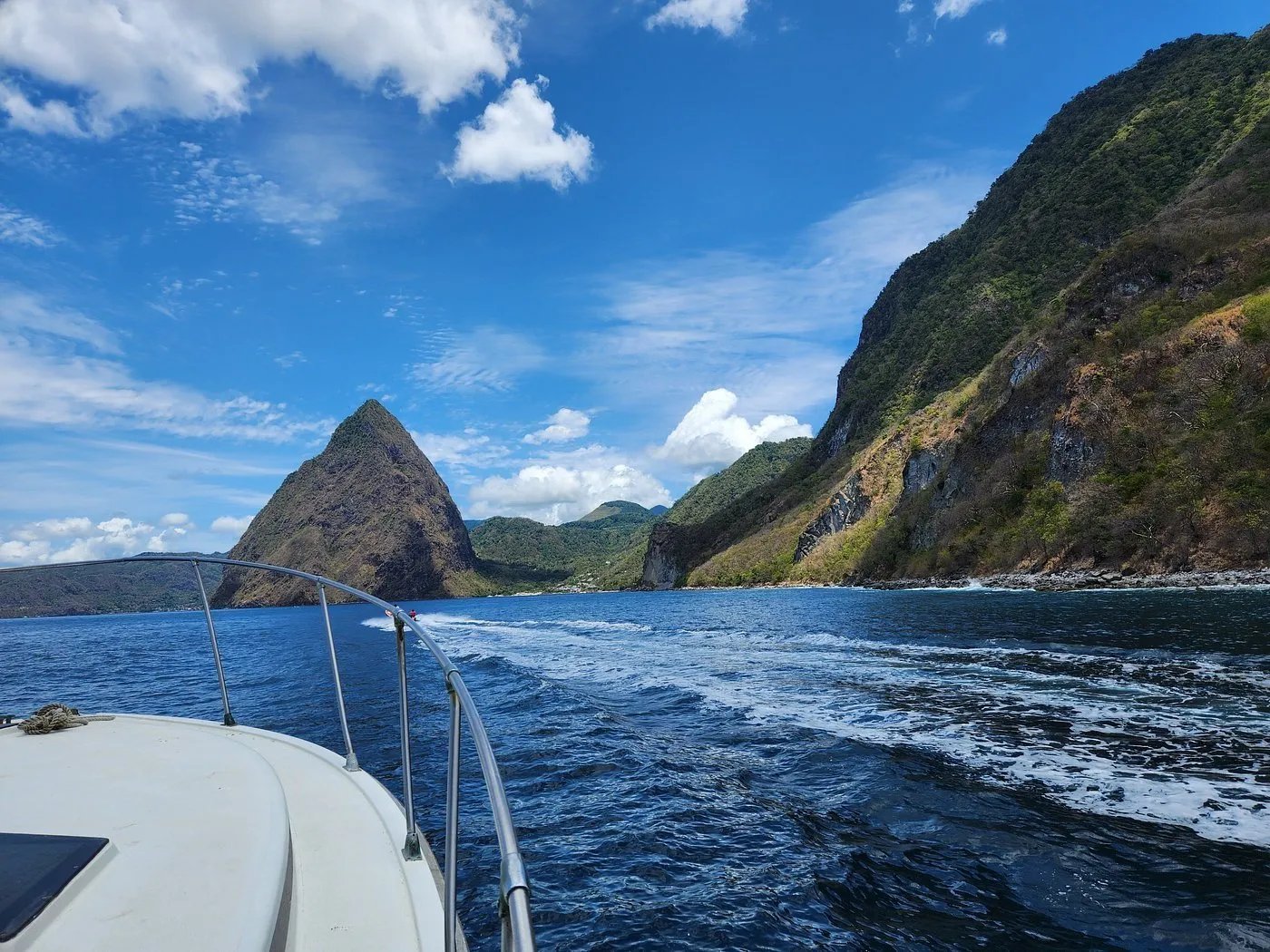Group of smiling tourists on a boat with the Pitons mountains in the background
