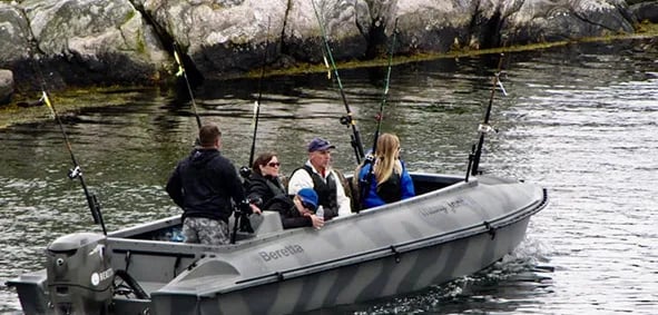Small boat with four anglers fishing in a calm bay with rocky shores.
