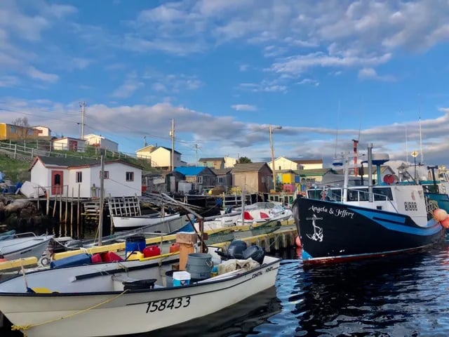 Colorful fishing village with boats docked in a harbor under a blue sky.