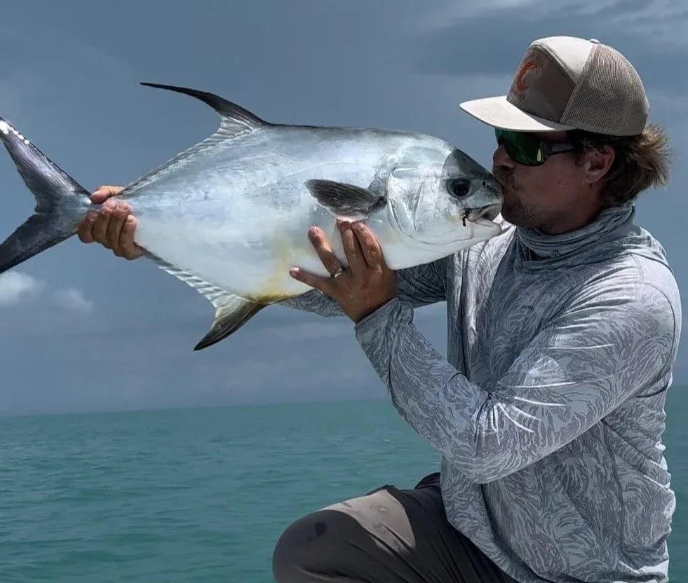 Angler kissing a large Permit on a boat.