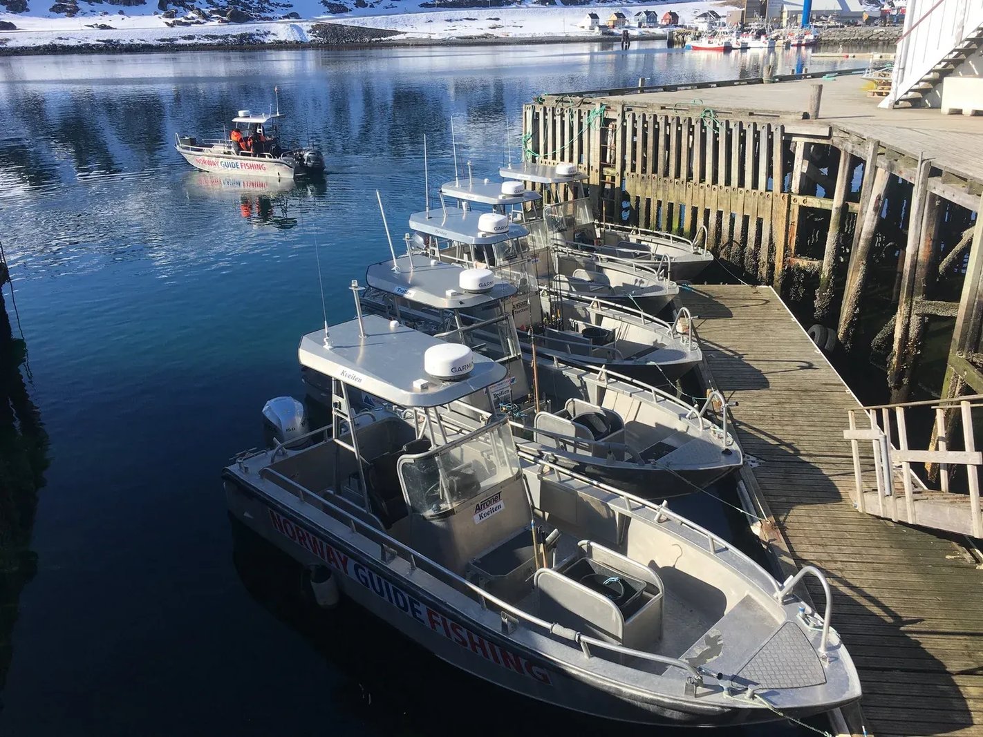 Fleet of fishing boats docked in a snowy harbor.