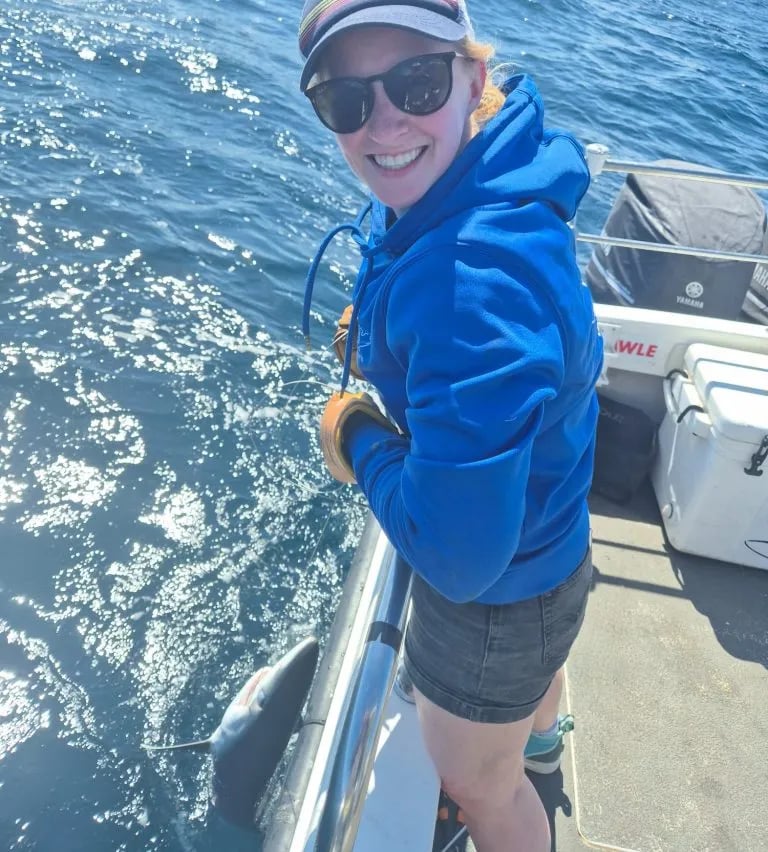 Round blue logo with a boat, two anglers, and a yellowfin tuna.