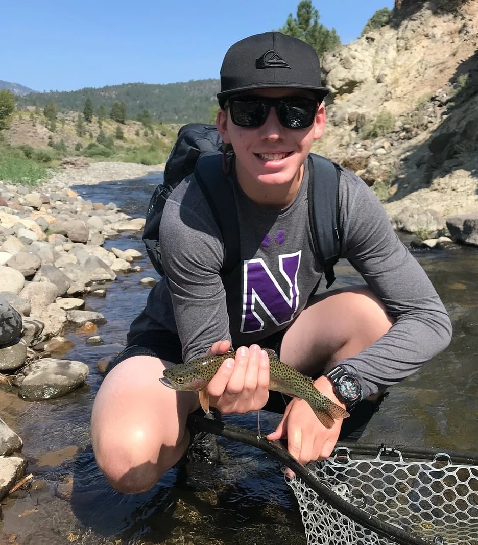 Two anglers holding a large Brown Trout in a river.
