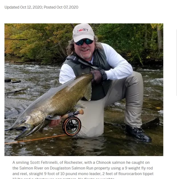 Angler holding a large Brown Trout in a river.