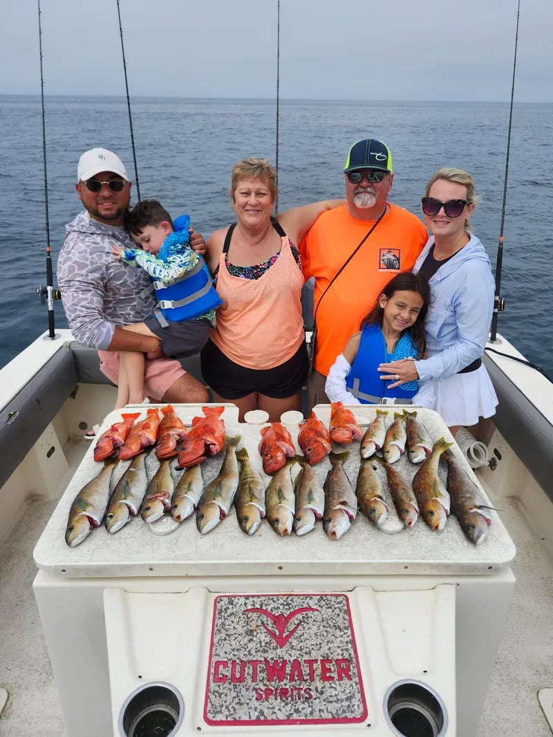 Child angler on a boat proudly holding a large Yellowtail by the tail