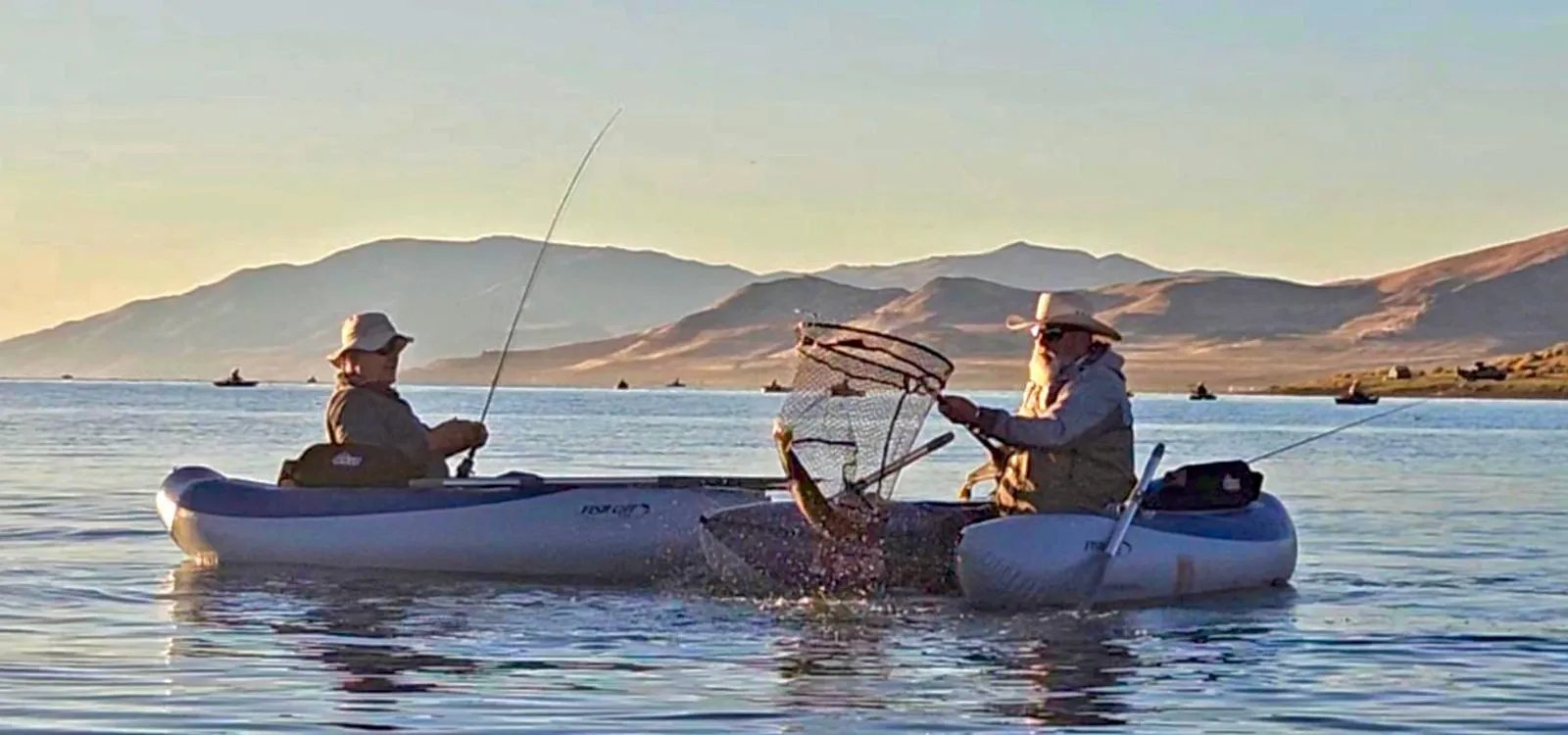 Two anglers holding a massive Cutthroat Trout on a sunny day.