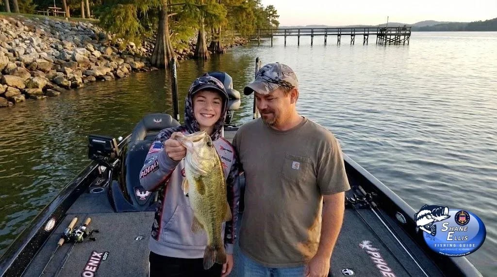 Father and son in a bass boat, son holding a Largemouth Bass.