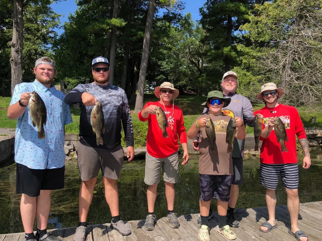Group of six anglers on a dock holding multiple Smallmouth Bass.
