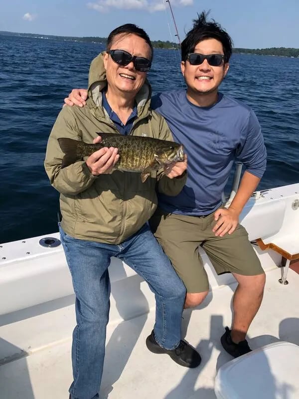 Young angler on a boat proudly holding a large Walleye.