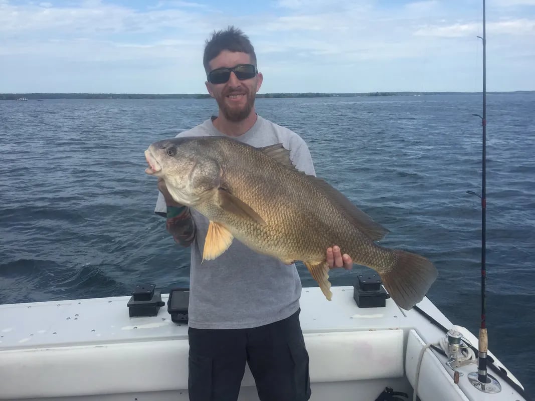 Two anglers on a boat, one holding a Smallmouth Bass.