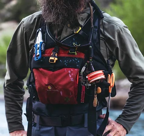Close-up of an angler wearing a red and black fishing vest with various tools