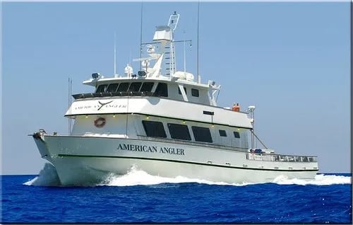 Large white fishing vessel 'American Angler' underway on clear blue water