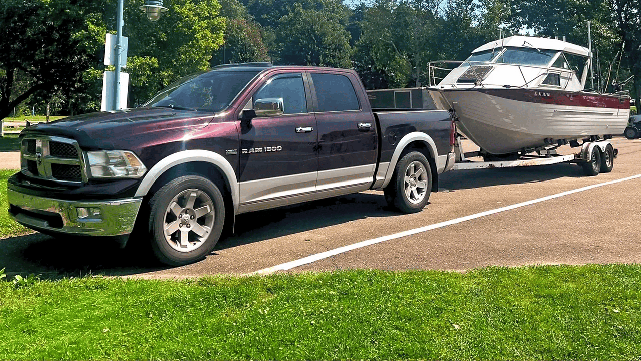 Maroon pickup truck towing a white and maroon fishing boat on a trailer