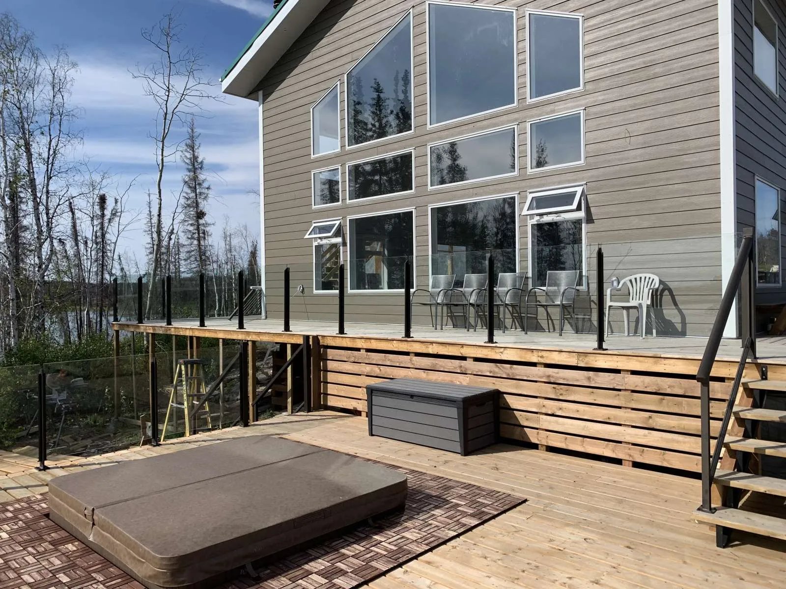 Namushka Lodge exterior with a large deck, glass railings, and a hot tub