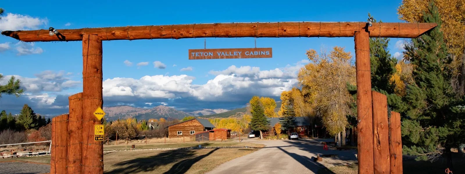 Wooden archway entrance to Teton Valley Cabins with mountains in the distance