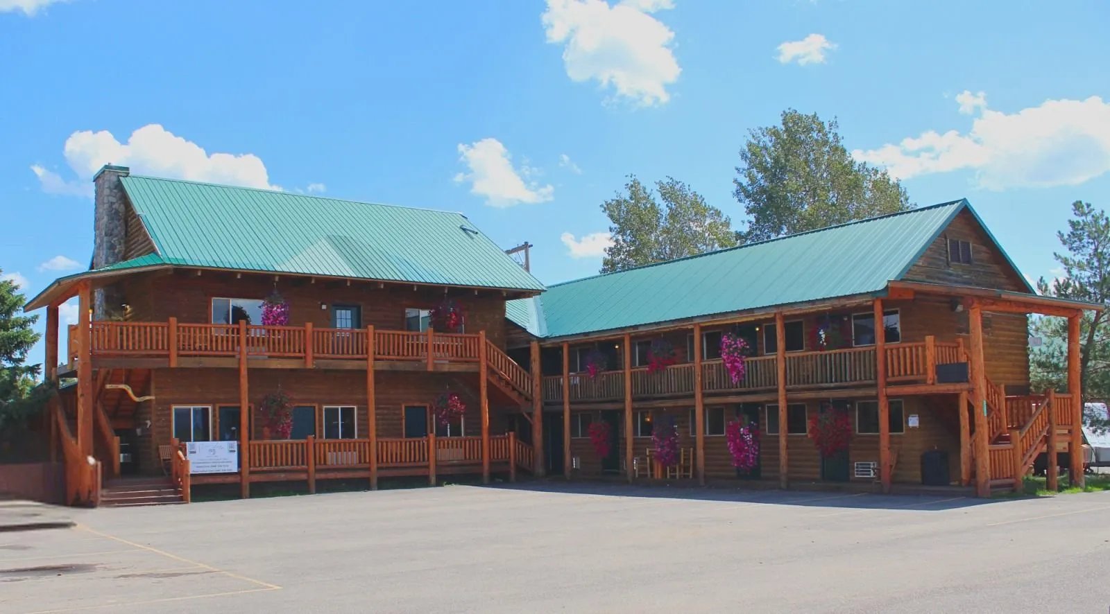 Wide view of a log cabin motel complex with green metal roofs and wooden balconies