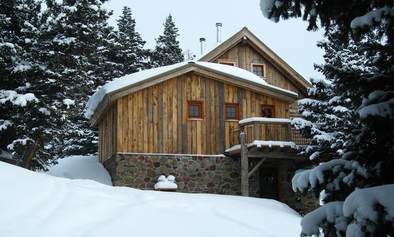 Wooden hut surrounded by snow-covered pine trees in winter.