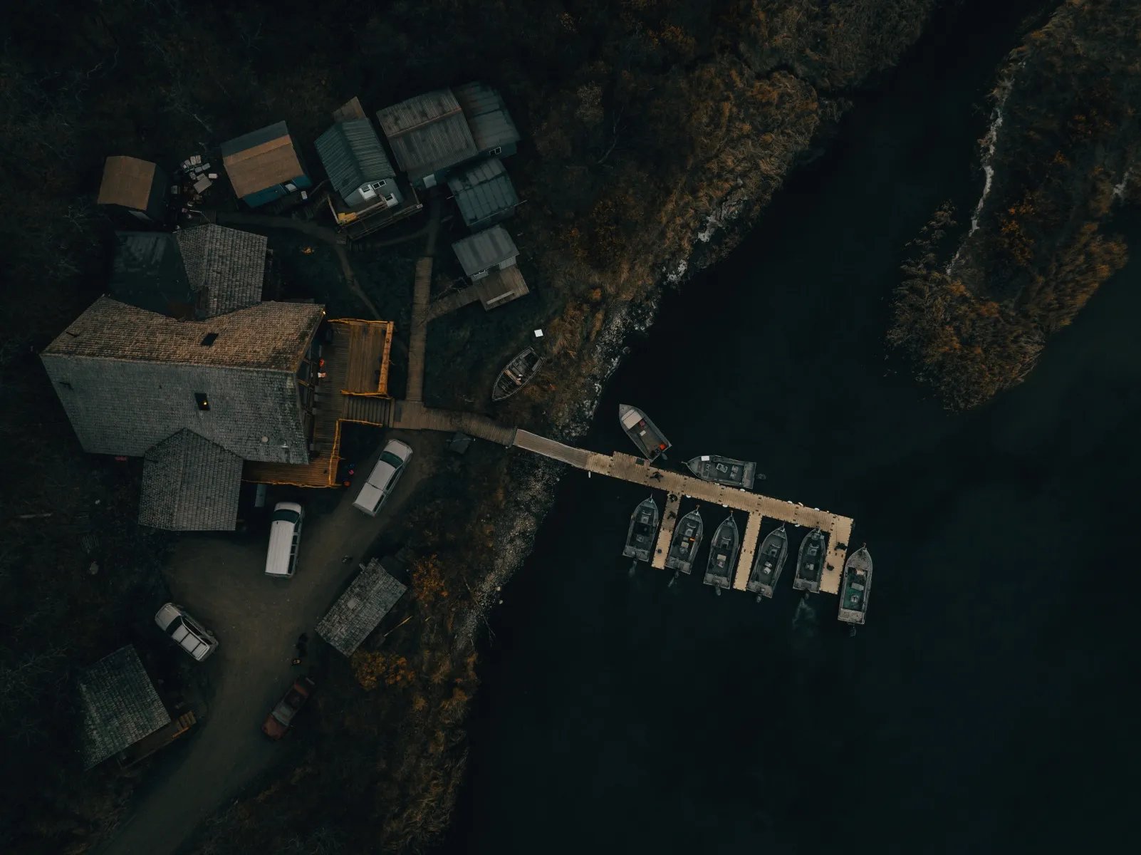 Top-down aerial view of Katmai Trophy Lodge buildings and a long dock with multiple boats.
