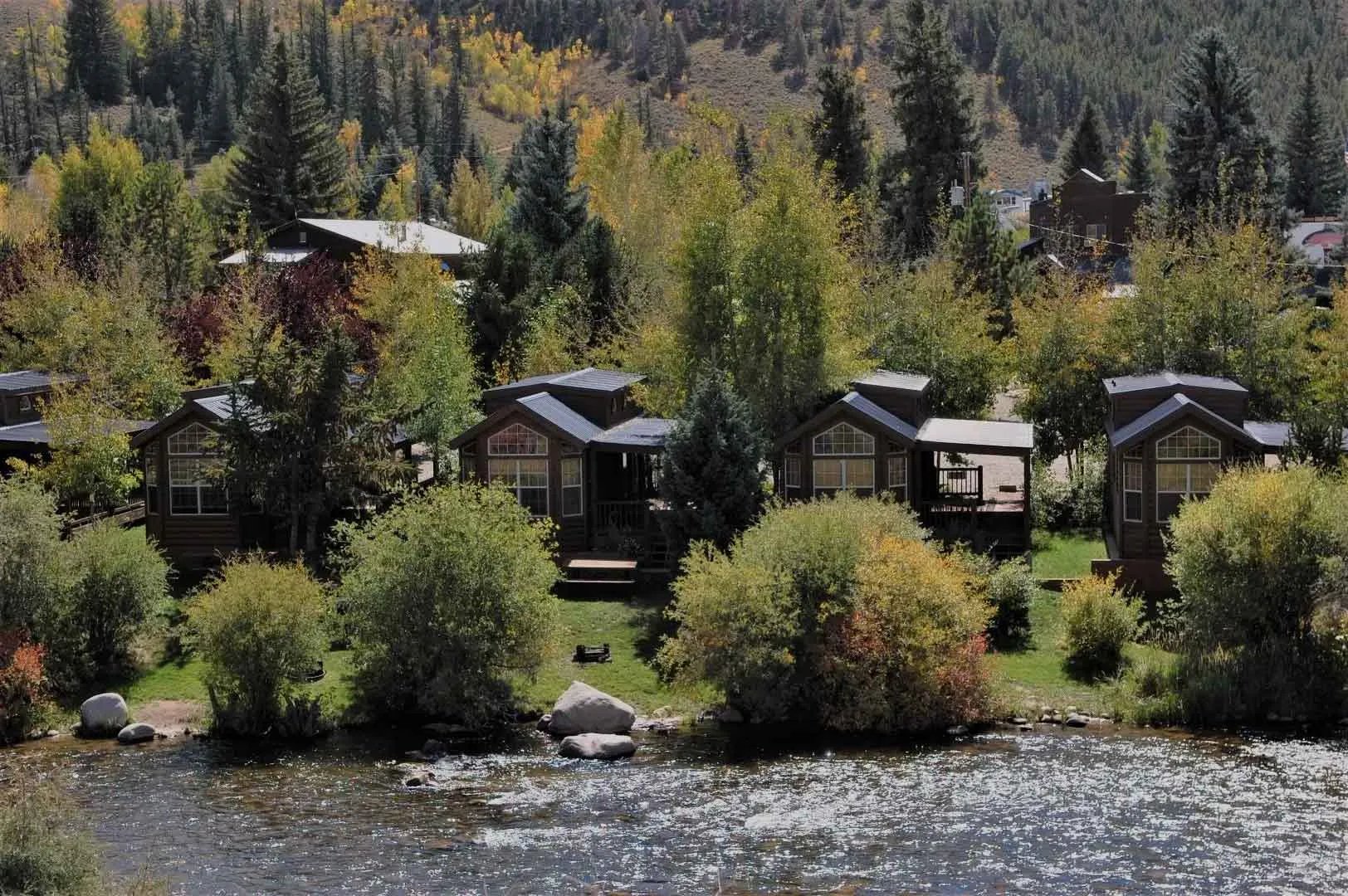 Aerial view of rustic cabins nestled among autumn trees along a river